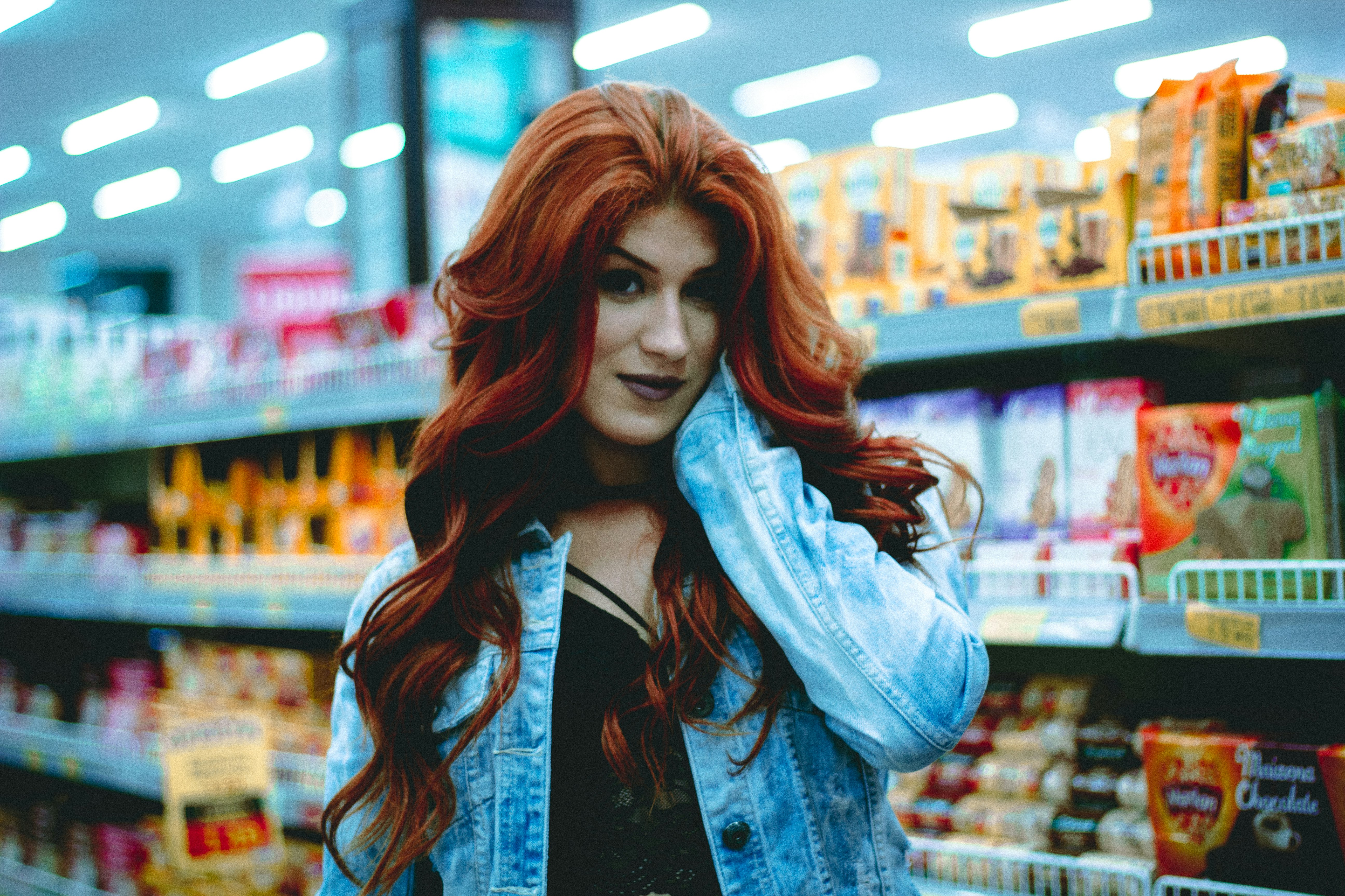 woman in blue denim jacket holding her face in convenient store